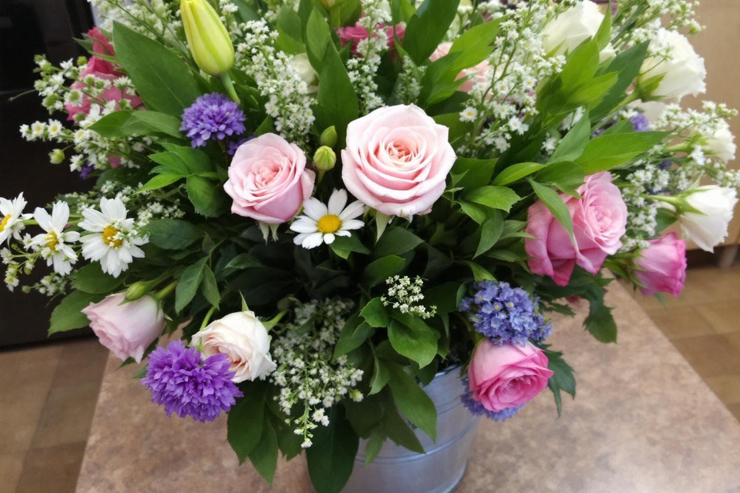 Fresh flowers in metal bucket with roses and daisies