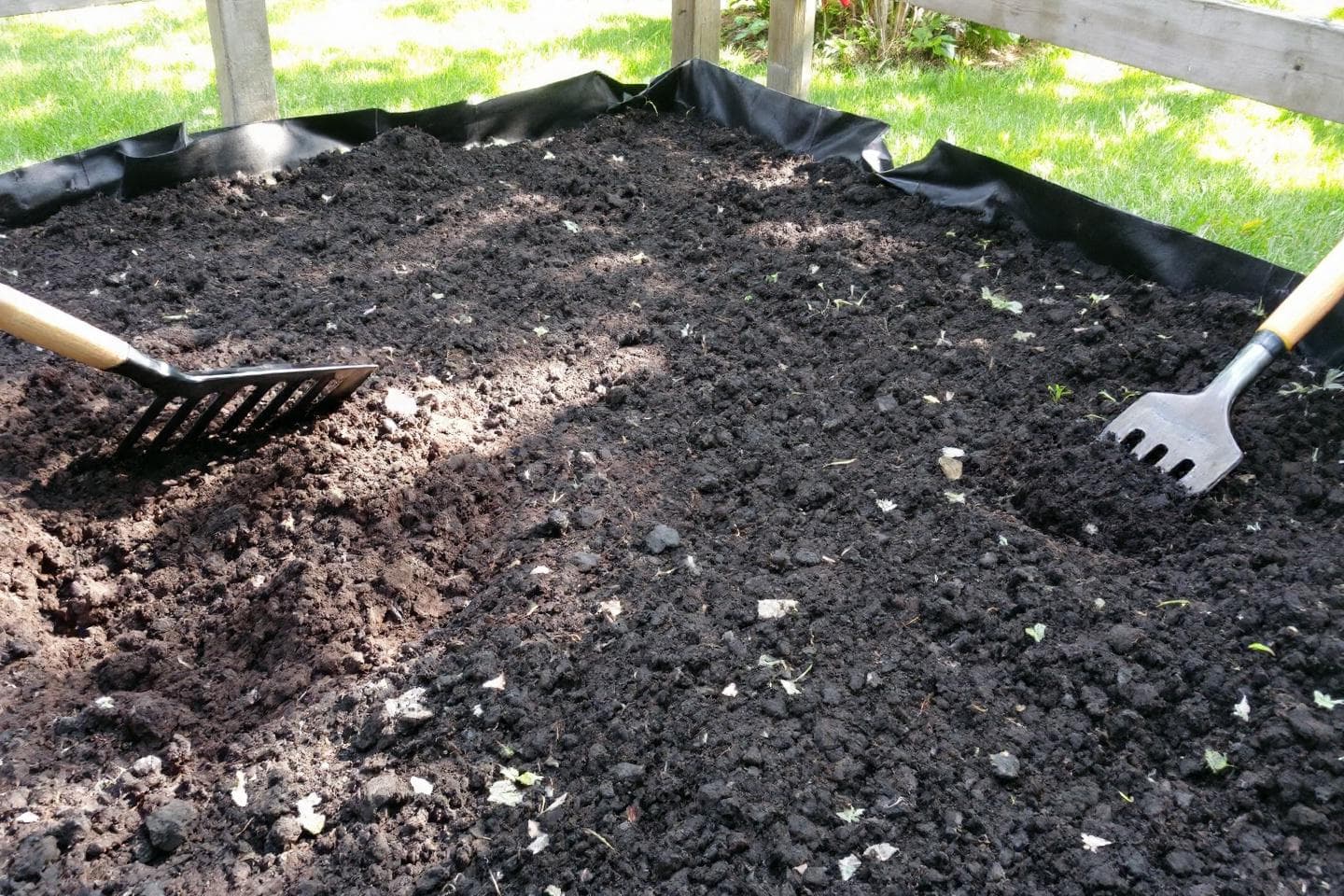 Garden bed with fresh soil ready for planting with rake and fork
