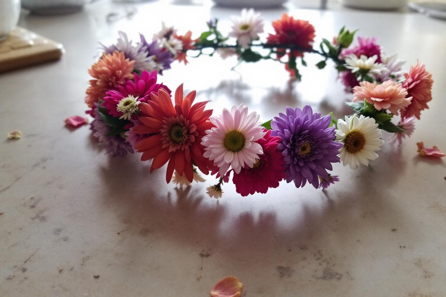 Colorful DIY flower crown with roses and daisies on wooden table